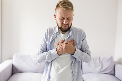 man holding his chest in pain with both hands due to a hiatal hernia attack