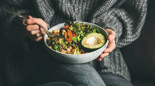 person sitting with plate of macrobiotic foods in a bowl