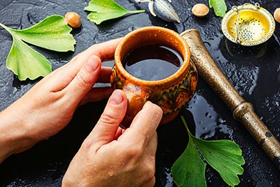 a persons hands holding a cup of ginkgo tea 