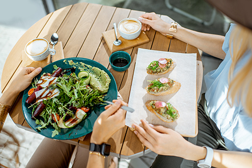 healthy food on a table while a woman waits with a fork to dig in