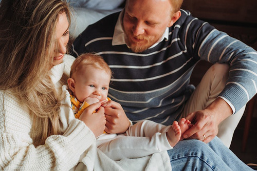 new mother and father cuddling up to new born baby
