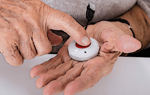 elderly person pressing the button of a medical alert device