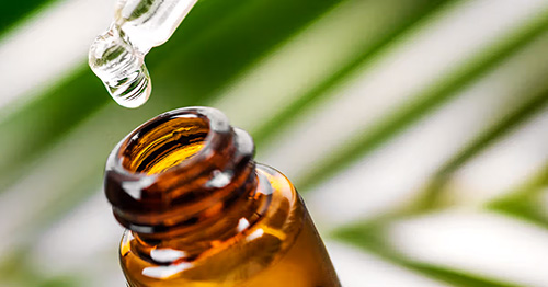 a dropper dropping essential oil into a bottle