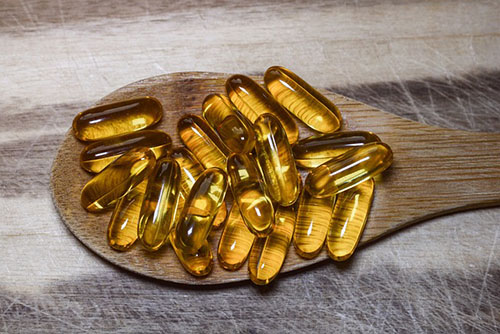 fish oil capsules on a wooden spoon