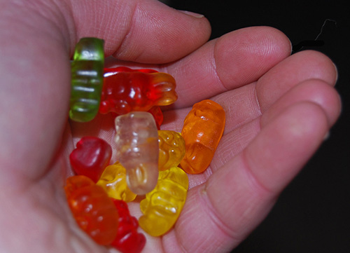 a hand filled with a wide array of colored gummies