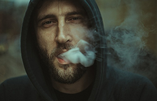 hooded man with smoke coming out his mouth