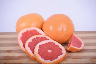 sliced grapefruit on a wooden cutting board.