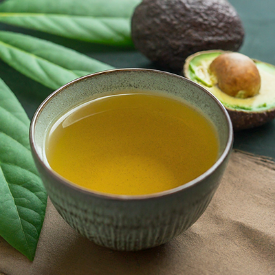 cup of avocado leaf tea with a half cut avocado in the background
