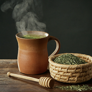 buchu leaves in a bowl along with a cup of tea