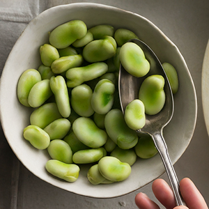 someone using a spoon to eat broad beans