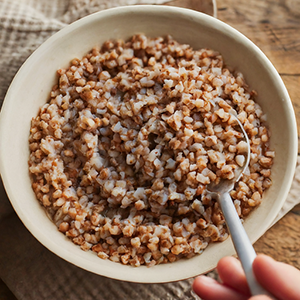 someone using a spoon to eat buckwheat